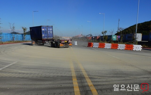 부산신항 서컨테이너 앞 도로가 운행차량이 배출한 토사로 오염된 모습.