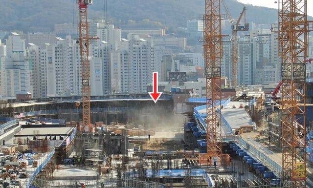 현대산업개발이 신축하는 부산 거제동 아파트 공사장에서 발생한 비산먼지가 대기 중에 흩날리고 모습(화살표). 사진=독자 제공