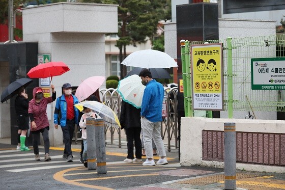 '봄비와 함께 돌아온 일상' 21일 대구 남구의 한 초등학교에서 우산을 들고 아이를 기다리는 학부모들. 사진=남경원 기자