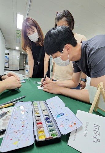 '구도와 모양은 이렇게' 18일 오후 대구 범어지하도상가 6, 7번 출구 일대 황도원 작가 캘리그라피 작품 전시회에서 가족들이 방문했다. 평소 캘리그라피를 그린다 던 한 시민이 직접 작가의 조언을 들으며 글을 그리고 있다. 사진=남경원 기자
