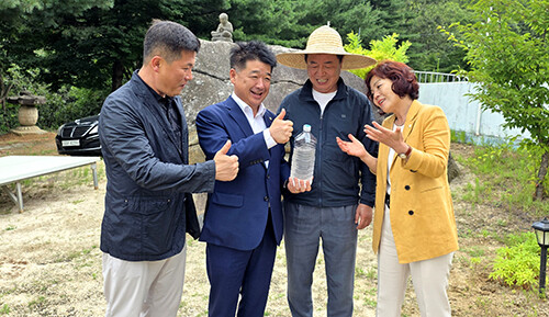 왕두꺼비 산장 식당 마당에 있는 두꺼비 바위 앞에서 금율약수를 들고 기념사진을 찍는 배형태(왼쪽부터) 김천시의원, 나영민 김천시의장, 신승우 대표. 김응숙 김천시의원. 사진=신승우 대표 제공