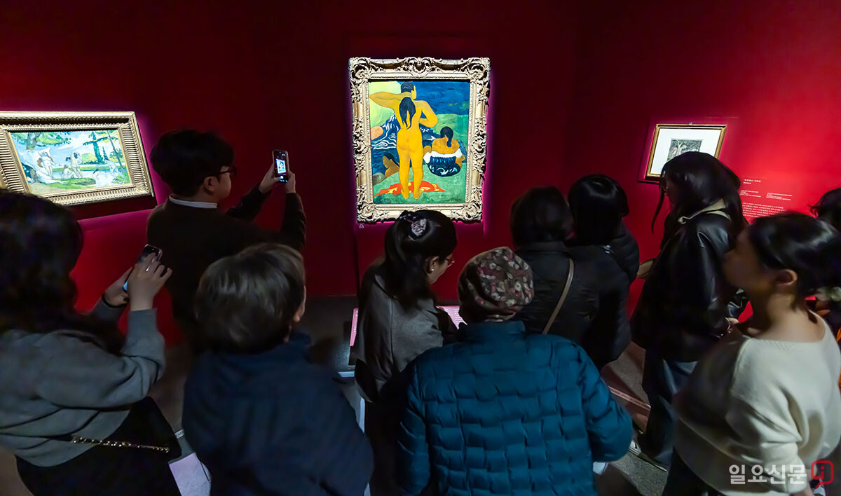 메트로폴리탄박물관 소장품전을 찾은 관람객들이 폴 고갱의 '타히티의 여인들'을 감상하고 있다. 강렬한 원색과 독특한 구도가 특징인 이 작품은 인상주의를 넘어선 고갱의 예술적 시도를 잘 보여준다.
