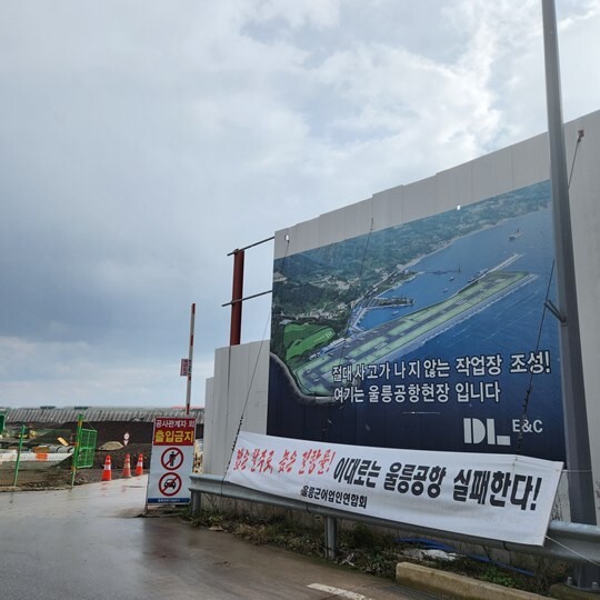울릉군어업인연합회 측이 '짧은 활주로, 높은 결항률! 이대로는 울릉공항 실패한다!' 문구가 적힌 현수막을 울릉공항 공사 현장 입구에 걸어 놓고 있다. 사진=김지영 기자