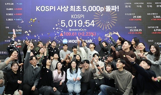 한국 증시가 사상 처음으로 '코스피 5000' 쾌거를 달성한 22일 서울 중구 우리은행 본점 딜링룸에서 직원들이 장중 최고가가 찍힌 전광판을 배경으로 코스피 5000 돌파를 축하하고 있다. 이날 코스피는 이재명 대통령이 '코스피 5000' 공약을 내걸고 임기를 시작한 지 7개월 만에 장중 꿈의 5000을 돌파하며 한국 자본시장의 역사를 새로 썼다. 사진=임준선 기자