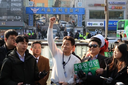 한국사 강사 출신 전한길 씨가 이재명 대통령 등에 대한 명예훼손 혐의로 조사 받기 위해 2월 12일 서울 동작경찰서로 출석하기 전 자신의 지지자들 앞에서 주먹을 불끈 쥐어 보이고 있다. 사진=연합뉴스