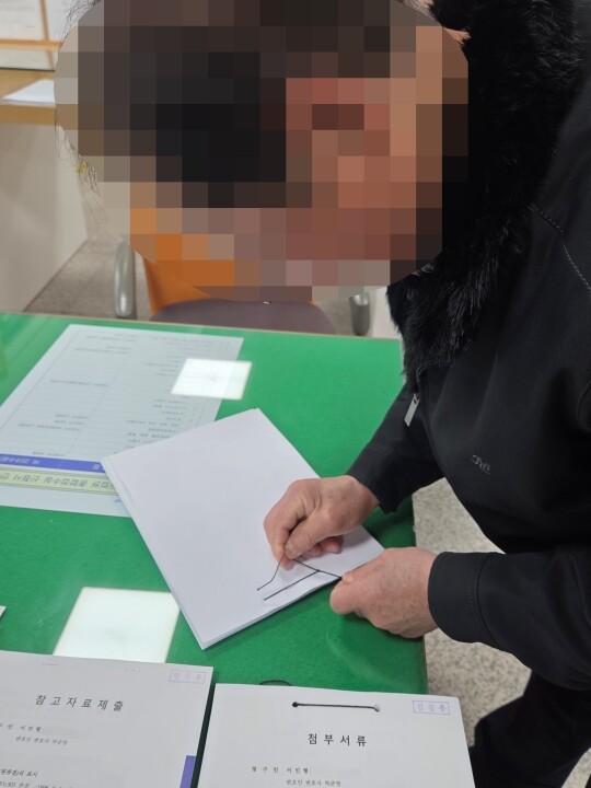 ‘대구 장미비디오 사건’의 범인으로 지목된 무기수 이민형 씨의 아버지가 지난 2월 9일 서울고등법원에 제출할 재심청구서를 편철하고 있다. 사진=최희주 기자